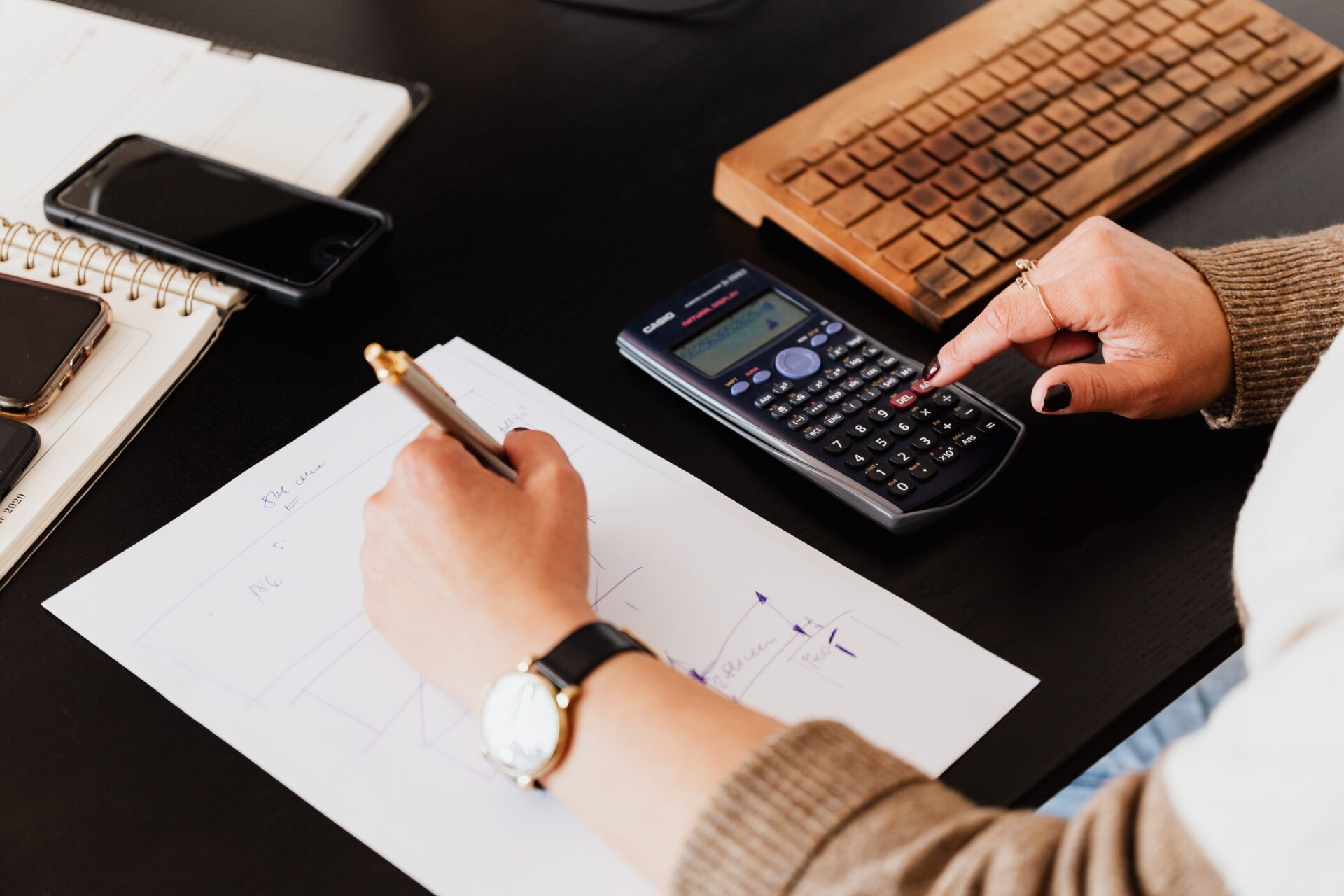 Bookkeeper Writing Down on Paper while using Calculator<br />
